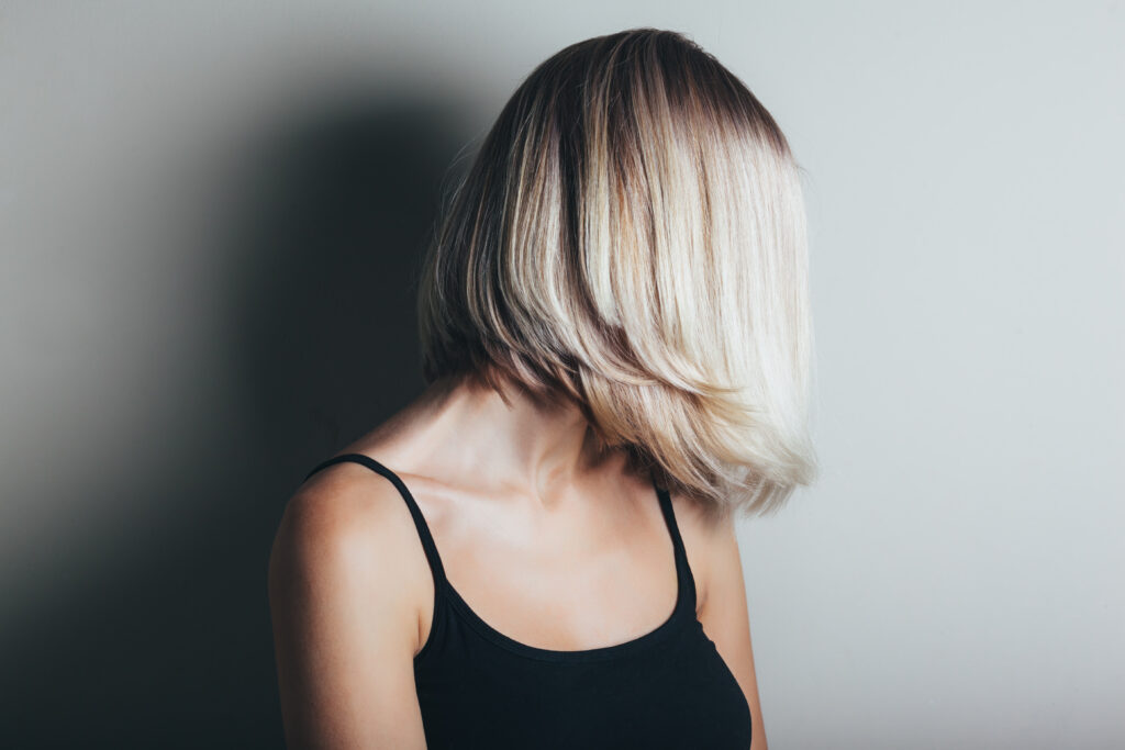 Model with unrecognizable face with blond shiny hair. Woman bob haircut styling.